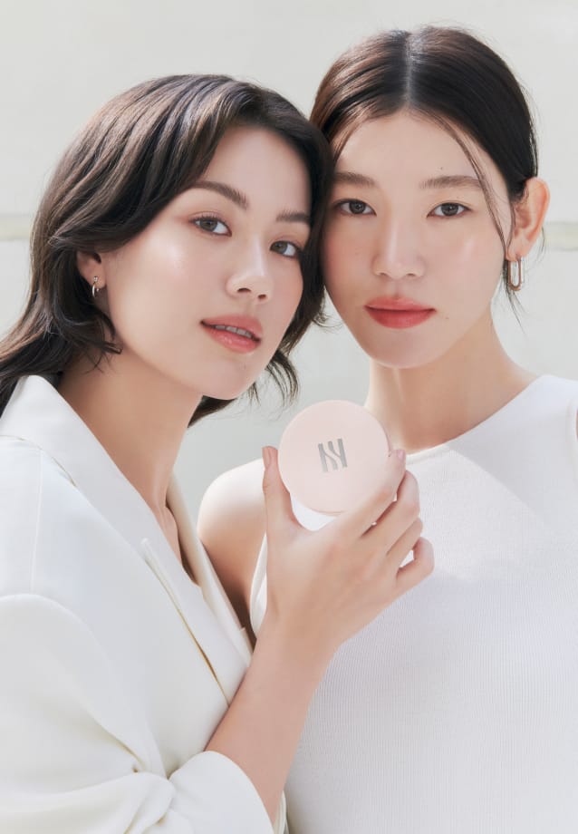 Models looking straight ahead while holding REFLECTION SKIN GLOW CUSHION FOUNDATION